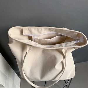 Detailed view of large canvas tote bag showing the interior compartment and zip pocket