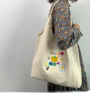 Detail of canvas tote bag with spring bear illustration and practical front pocket