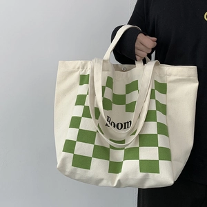 Detail view of the green checkerboard pattern and black Room text on a beige canvas tote bag