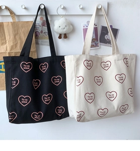 Détail de sacs fourre-tout en toile avec cœur rouge et texte imprimé Tu es aimé
