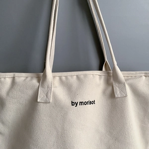 Close-up of oatmeal canvas tote bag with black by morisot print and dual straps