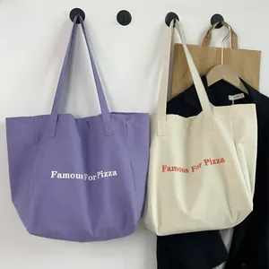 Gros plan de sacs cabas en toile violets et crème avec impression Famous For Pizza
