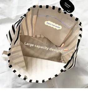 Detail view showing magnetic closure and internal zipper pocket of striped canvas tote