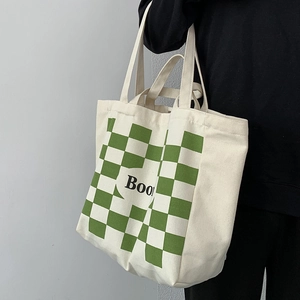 Detail of canvas tote bag featuring green checkerboard pattern and Book text print