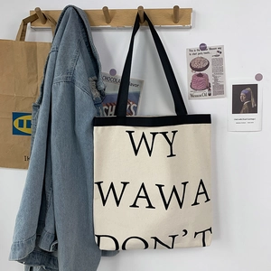 Minimalist off-white canvas tote bag with black straps and bold letter print design