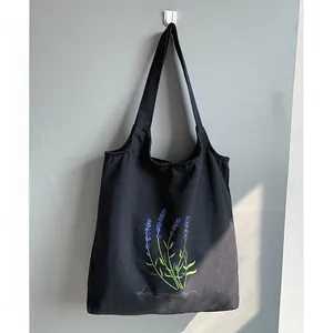 Close-up of black canvas tote bag featuring purple lavender floral embroidery detail