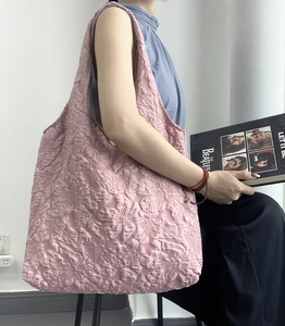 Détail de la texture jacquard à fleurs du sac cabas rose avec bandoulière minimaliste
