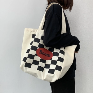 Detail of checkered canvas tote bag with red Boom logo and cream shoulder straps