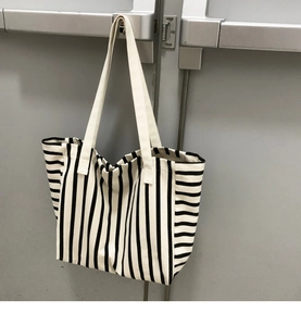 Detail of a large canvas striped tote bag with reinforced handles and durable texture