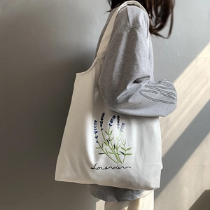 Detailed view of white canvas tote bag with purple lavender print and soft side lighting