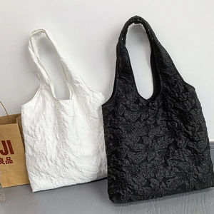 Vue détaillée de la texture brodée de roses sur des sacs fourre-tout blanc et noir