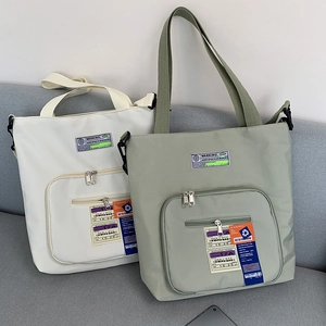 Nahaufnahme von beigen und grünen Nylon-Tote-Bags mit Reißverschlusstaschen auf Sofa