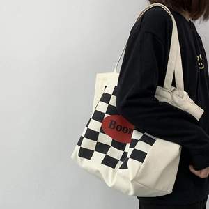 Detail of canvas tote bag with black and white checkerboard pattern and Boom text print