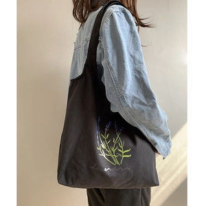 Close-up of black canvas tote bag featuring a purple lavender print and text