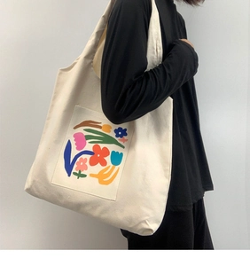 Canvas tote bag with colorful abstract floral print shown worn on a female model shoulder