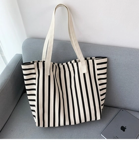 Detailed view of large black and white striped canvas tote bag on a modern gray sofa