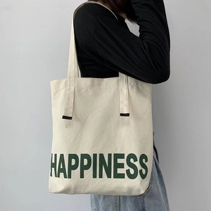 Détail du sac fourre-tout en toile crème avec imprimé Happiness vert et bandoulières renforcées
