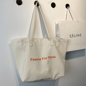 Détail d'un grand sac cabas en toile avec lettrage orange et bandoulières robustes
