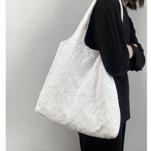 Détail de la texture jacquard à fleurs blanches sur ce grand sac fourre-tout épuré