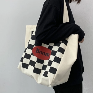 Side view of a large canvas tote bag with red Boom logo and checkerboard print