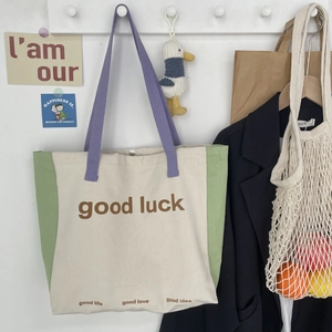 Canvas tote bag in cream and green with purple handles and good luck slogan