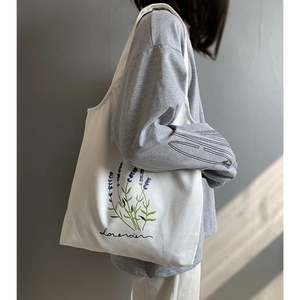 Detail of white canvas tote bag featuring lavender floral print on a female model