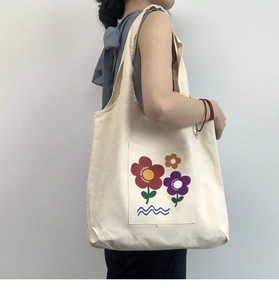 Detail of a large white canvas tote bag with floral prints and happy birthday text