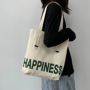 Détail du sac à épaule en toile blanc cassé avec inscription Happiness en vert forêt