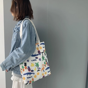 Detailed view of white canvas tote bag with colorful summer tropical prints worn by model