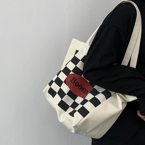 Detail view of large canvas tote bag with black and white plaid pattern and red Boom logo