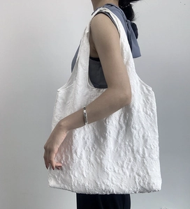 Vue détaillée d'un sac cabas blanc avec jacquard floral 3D et tissu à texture de bulles