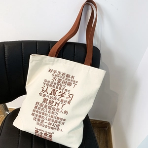 Large canvas tote bag with brown straps and inspirational text on a leather chair