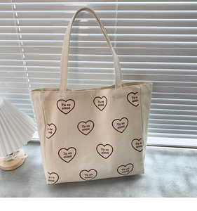 Détail du sac cabas en toile crème avec motif de cœurs rouges et texte Tu es aimé
