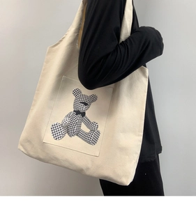Detail of off-white canvas tote bag featuring a cute houndstooth bear print accent