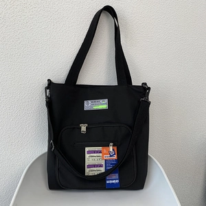 Nahaufnahme einer schwarzen Nylon-Tasche mit Retro-Flugetikett und Streetwear-Grafik