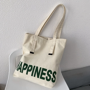 Détail du sac cabas en toile blanc cassé avec lettrage Happiness vert et bouton pression