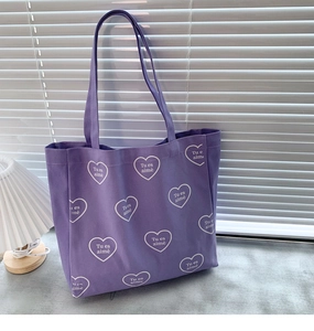 Détail du sac cabas en toile violette avec motifs cœurs blancs et texte Tu es aimé