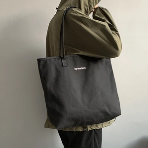 Minimalist black canvas tote bag with white Morisot text for daily travel use