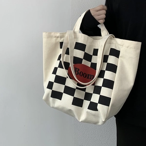 Close-up of a cream canvas tote bag featuring a checkerboard pattern and a red Boom label