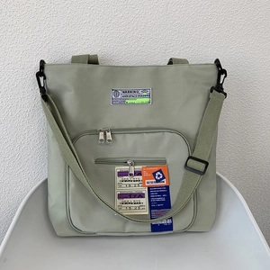 Detail der salbeigrünen Nylon-Tragetasche mit Cargo-Taschen und Etiketten im Techwear-Stil