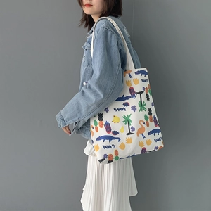 Side view of white canvas tote bag with Hawaii print worn by model in denim jacket