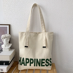 Détail du sac fourre-tout en toile blanc cassé avec imprimé HAPPINESS vert et bouton pression
