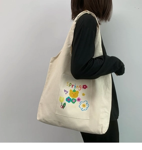 Detail of a white canvas tote bag with colorful spring bear print worn on shoulder