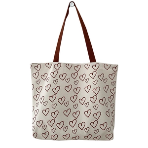 Minimalist canvas tote bag with red heart pattern and brown handles in a front view