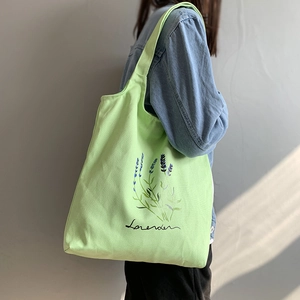Detail of light green canvas tote bag with lavender print and long shoulder strap