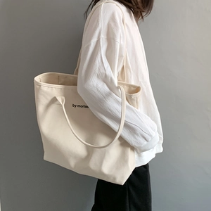 Detail view of cream canvas tote bag showing by moriso logo and durable long handles