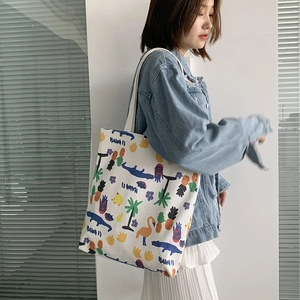 Detail view of a white canvas tote bag with colorful Hawaii themed prints and shoulder strap