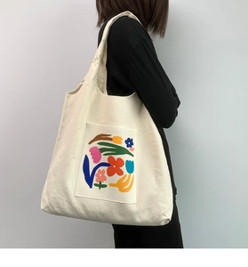 Detail of white canvas tote bag featuring an artistic abstract floral print on the pocket