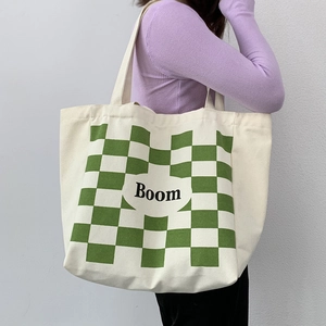 Detail view of large canvas tote bag with green checkerboard pattern and Boom lettering