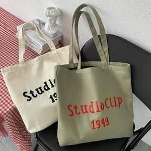 Detail of StudioClip 1949 canvas tote bags in beige and olive on a metal chair